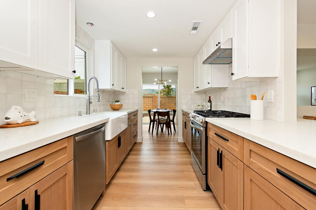 Modern kitchen with white cabinets and  oak cabinets, wooden floor, and stainless steel appliances.