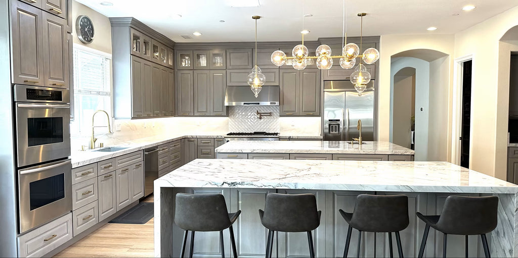 Modern kitchen with marble island, stainless steel appliances, and pendant lights.