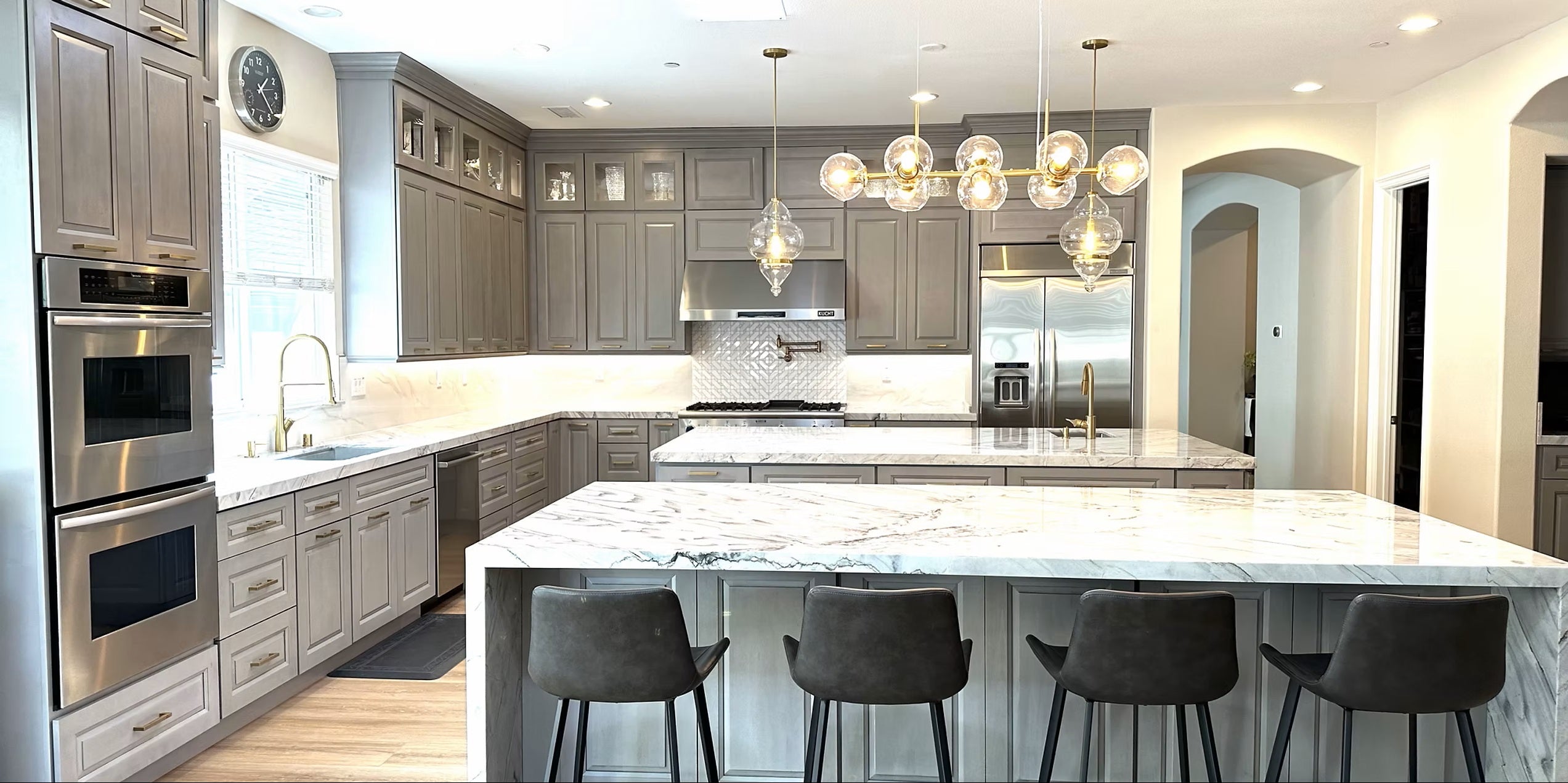 Modern kitchen with marble island, stainless steel appliances, and pendant lights.