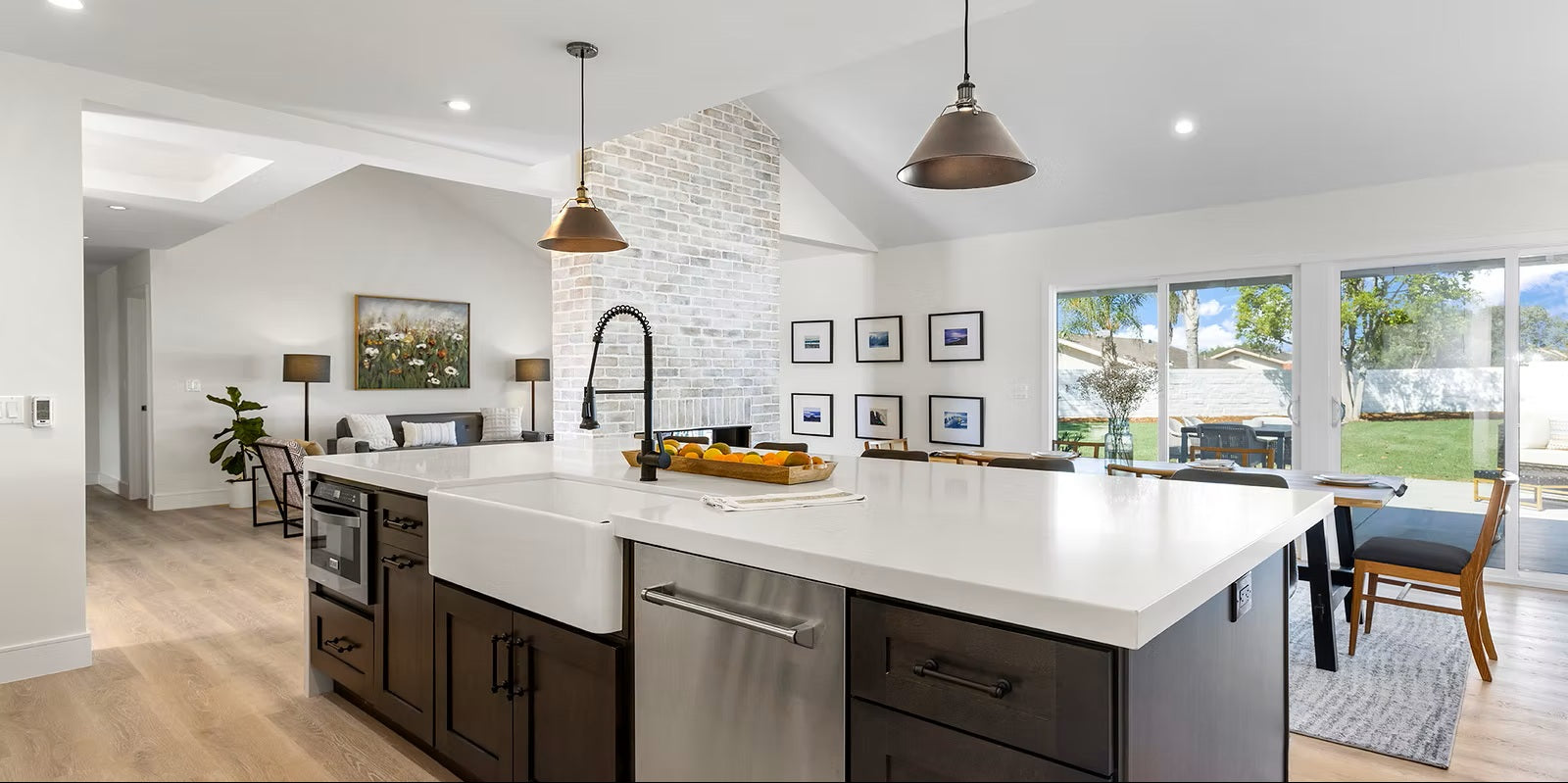Modern kitchen with white island, stainless steel appliances, and large windows.